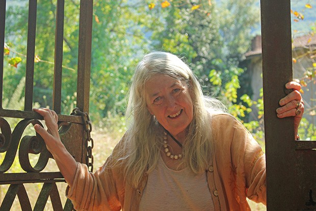 Mary Beard’s new series focuses on the lives of everyday citizens rather than the achievements of the Roman elite. (Photo by BBC) A photo of Mary Beard, smiling and looking towards the camera, standing between open gates.